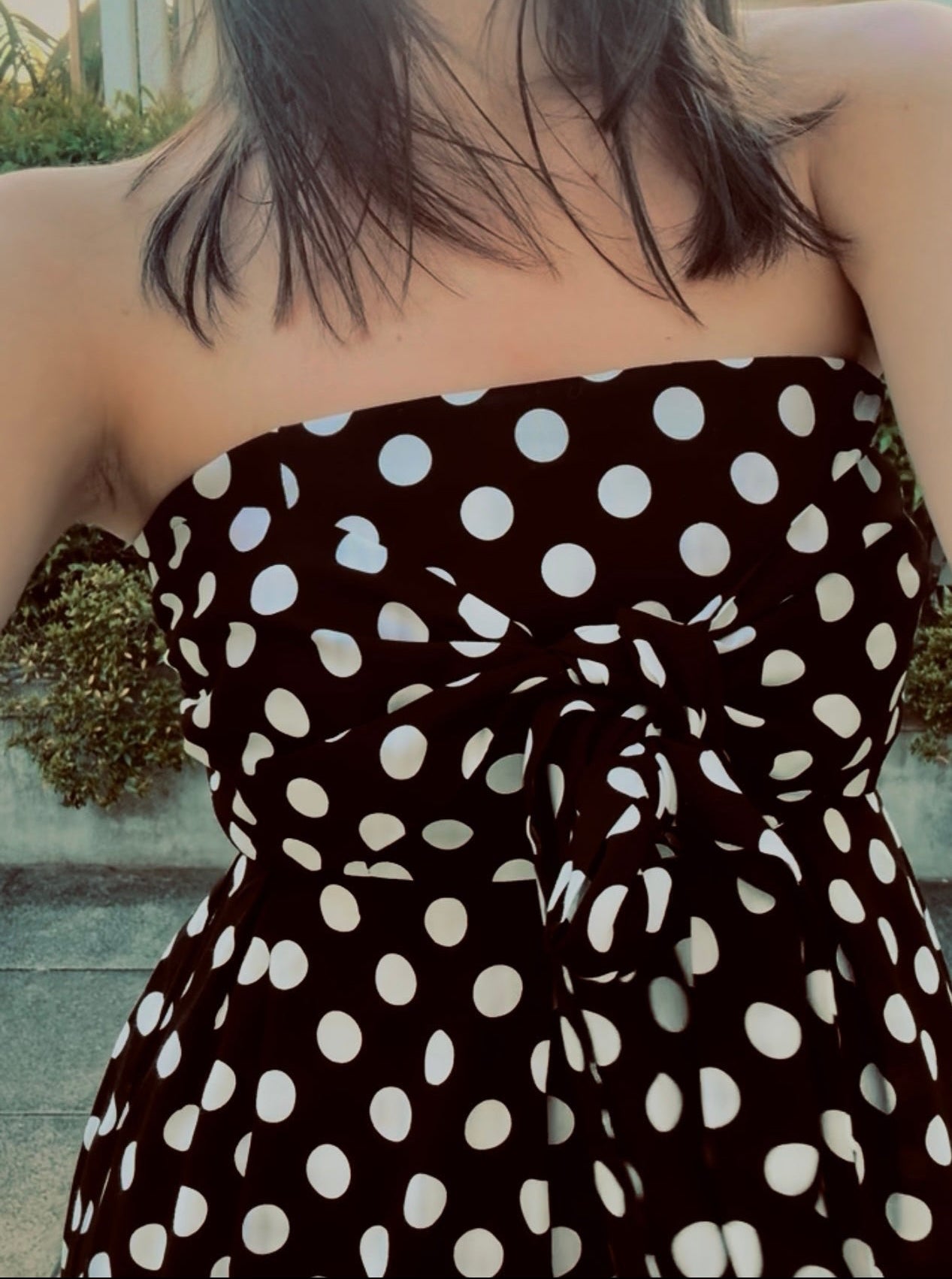 Black strapless dress with white polka dots worn by a person outdoors.