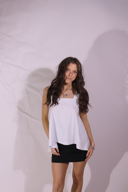 Woman in a white top and black skirt standing on a white background
